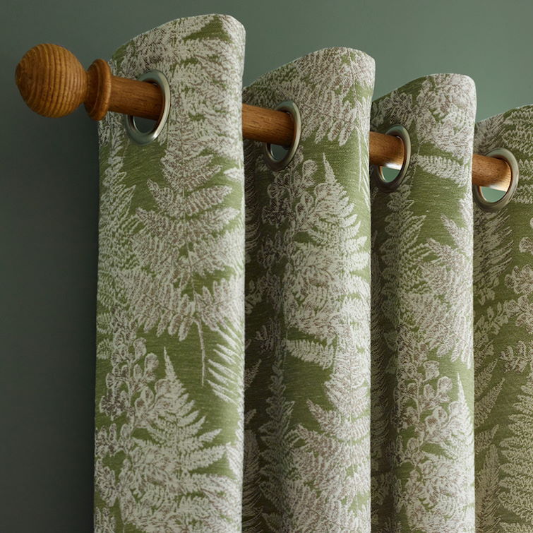 close up photo of floral green curtains hanging on wooden curtain pole 