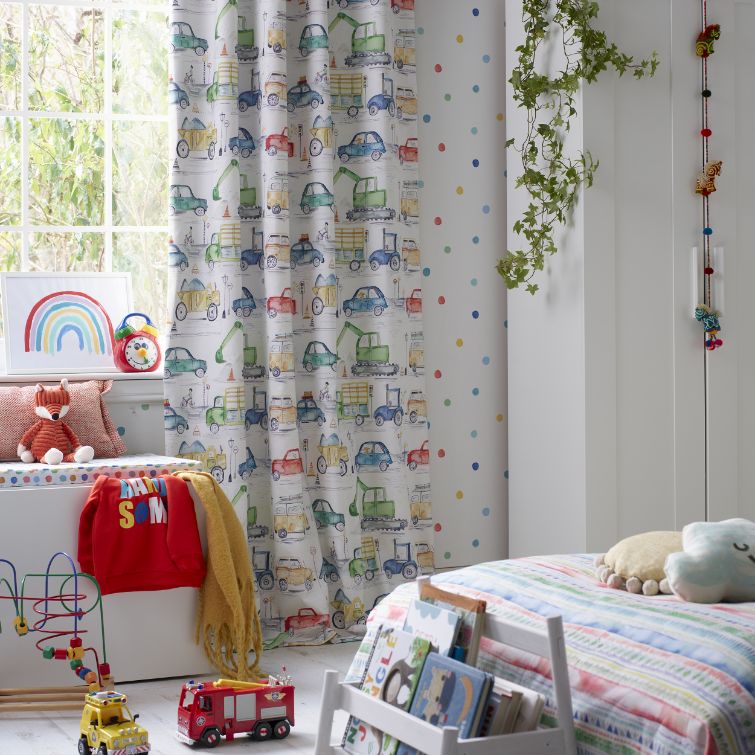 Photo of a children's room with bed next to window with curtains with car print hanging
