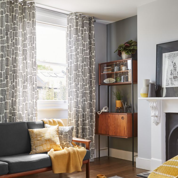 photo of grey and yellow themed living room with yellow cushions and grey eyelet curtains 