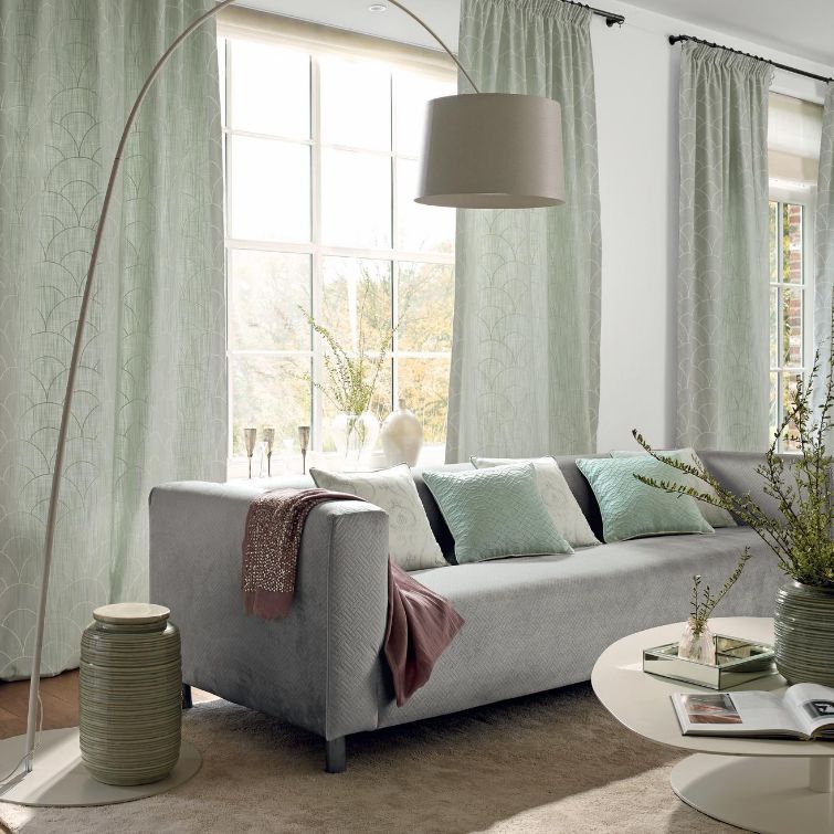 photo of grey sofa underneath hanging lampshade next to large window with green living room curtains fitted 