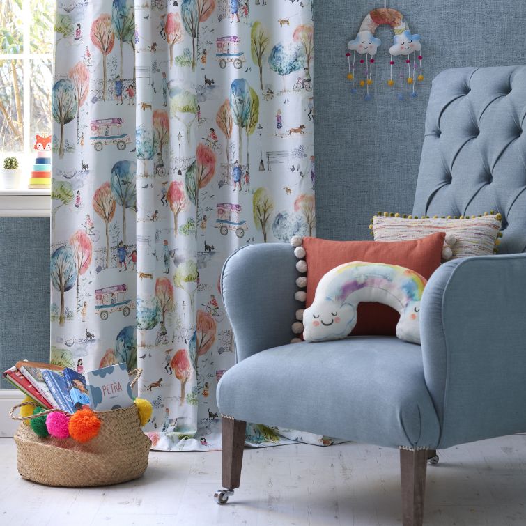 close up photo of blue chair next to window with nursery curtains 