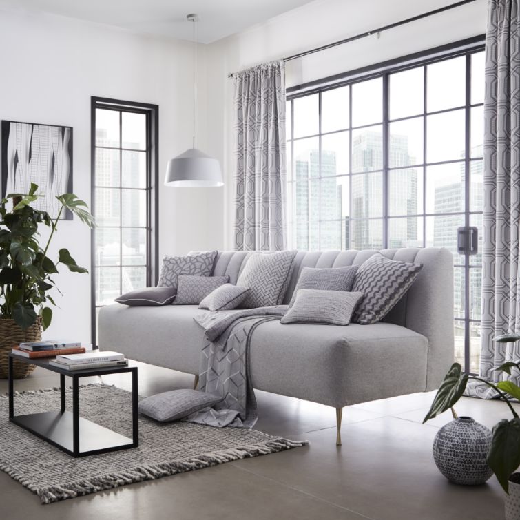 photo of grey sofa infront of two large windows with geometric patterned grey thermal curtains attached 
