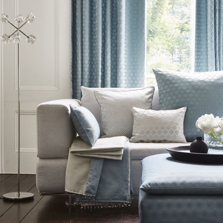 close up image of grey sofa with blue cushions in front of blue wave curtains 