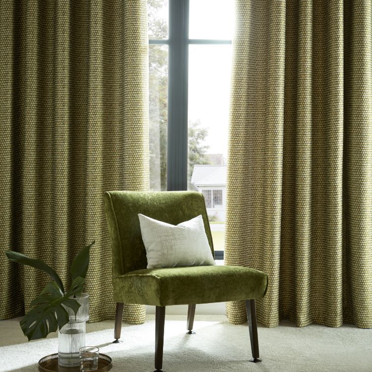 image of green chair infront of large window with dark green wave curtains 
