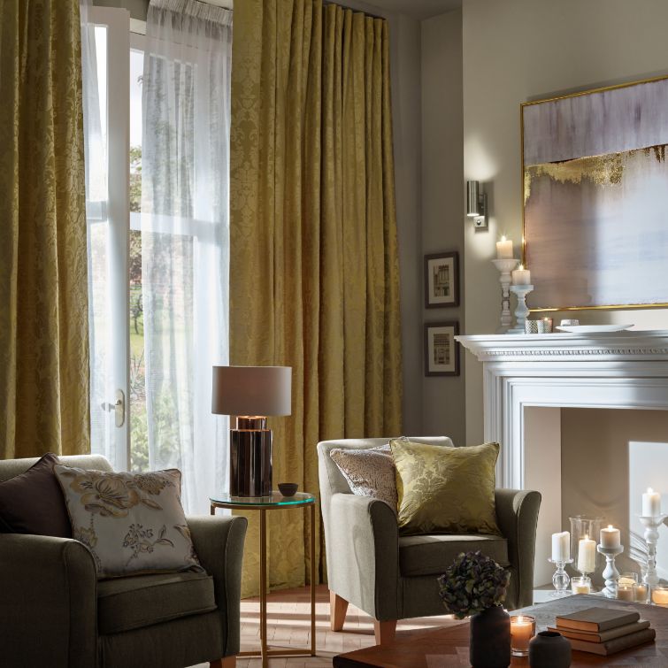 Image of two chairs in a living room with gold wave curtains on the window behind 