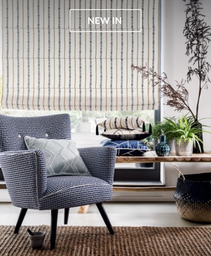 Roman Blinds in a contemporary living space with a blue armchair and plants.
