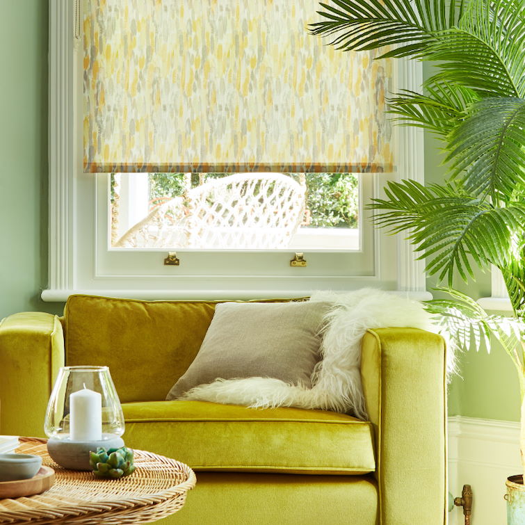 image of green themed living room with house plant and light green sofa next to window dressed with light green roller blinds