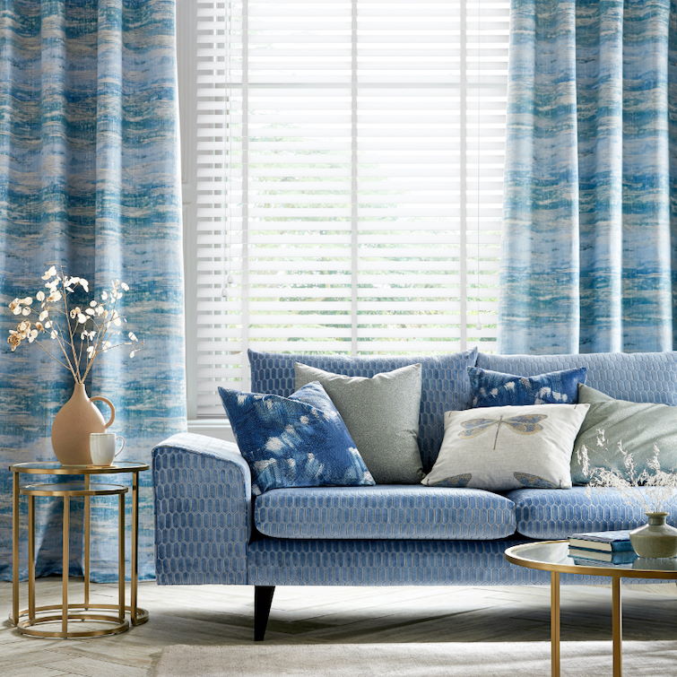 image of living room with different shades of blue and sofa and curtains next to cream house plant